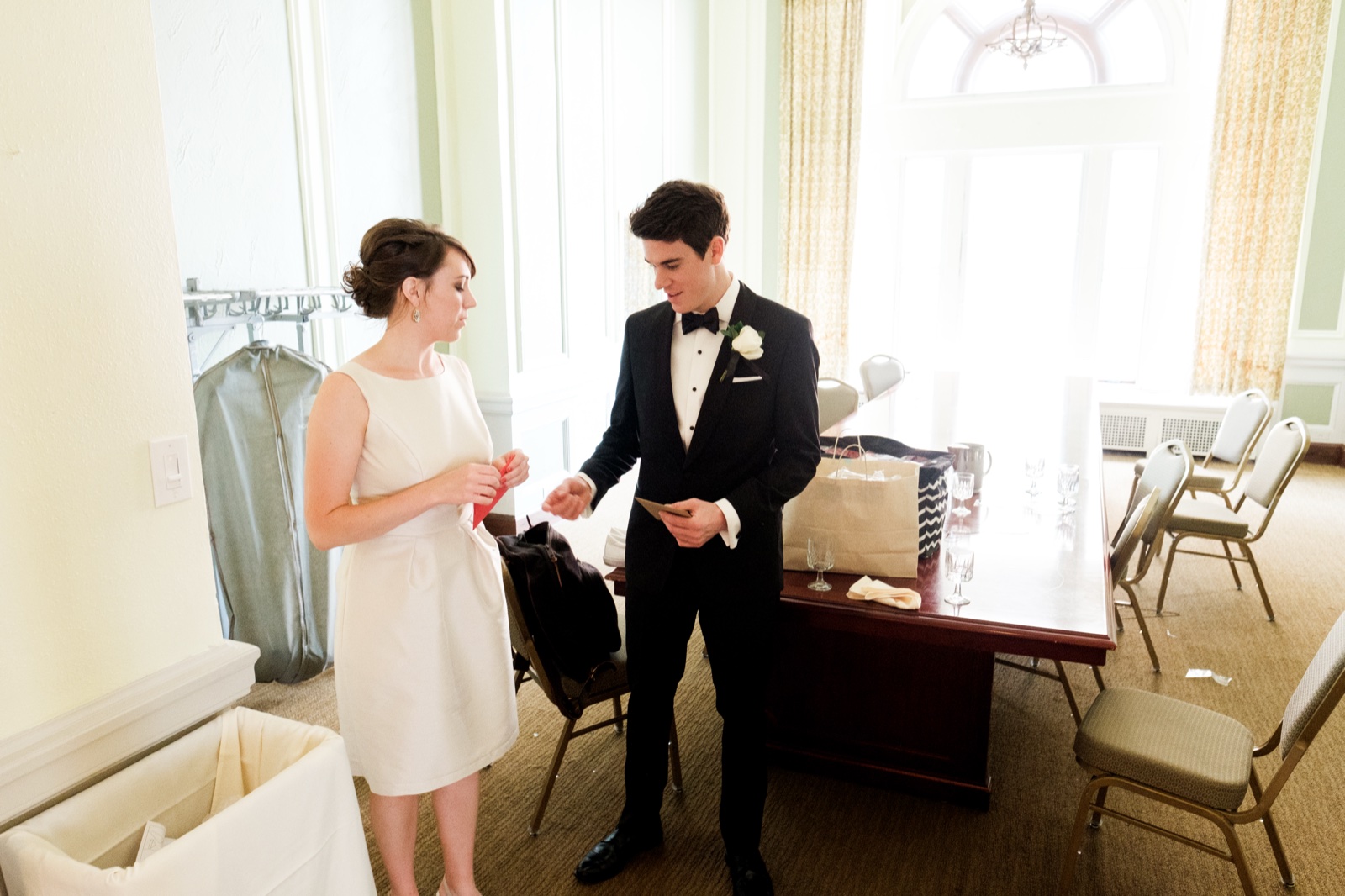 The bride and groom stand in a bright window-lit ballroom exchanging handwritten vow notes before the walk to the Cathedral — Tim Larsen Photography, Duluth MN
