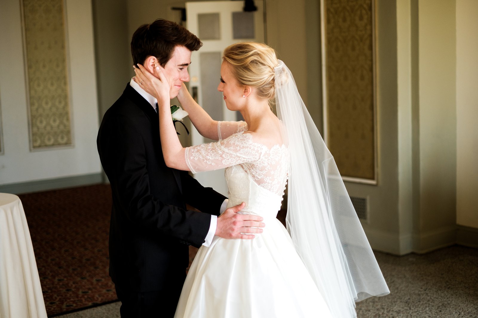 The bride cradles the groom's face as he tears up during their first look inside the ornate Greysolon Plaza — Tim Larsen Photography, Duluth MN