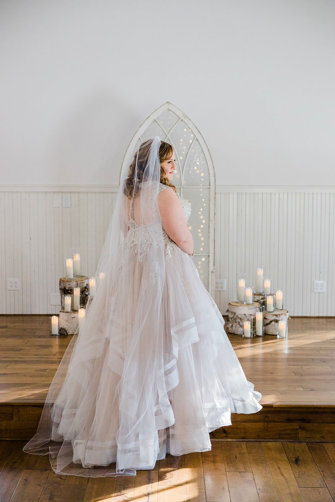 Bridal portrait from behind — tiered tulle gown and cathedral veil with candles and gothic arch — Tim Larsen Photography, Brainerd Lakes MN