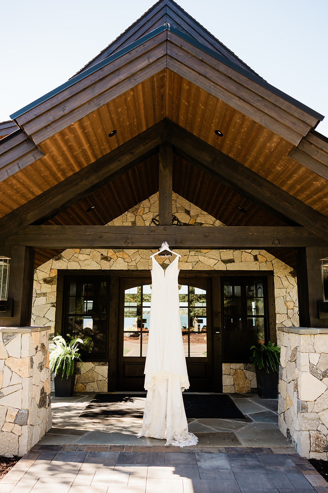 Wedding dress hanging at the stone and timber entrance of The Cove on Whitefish Lake