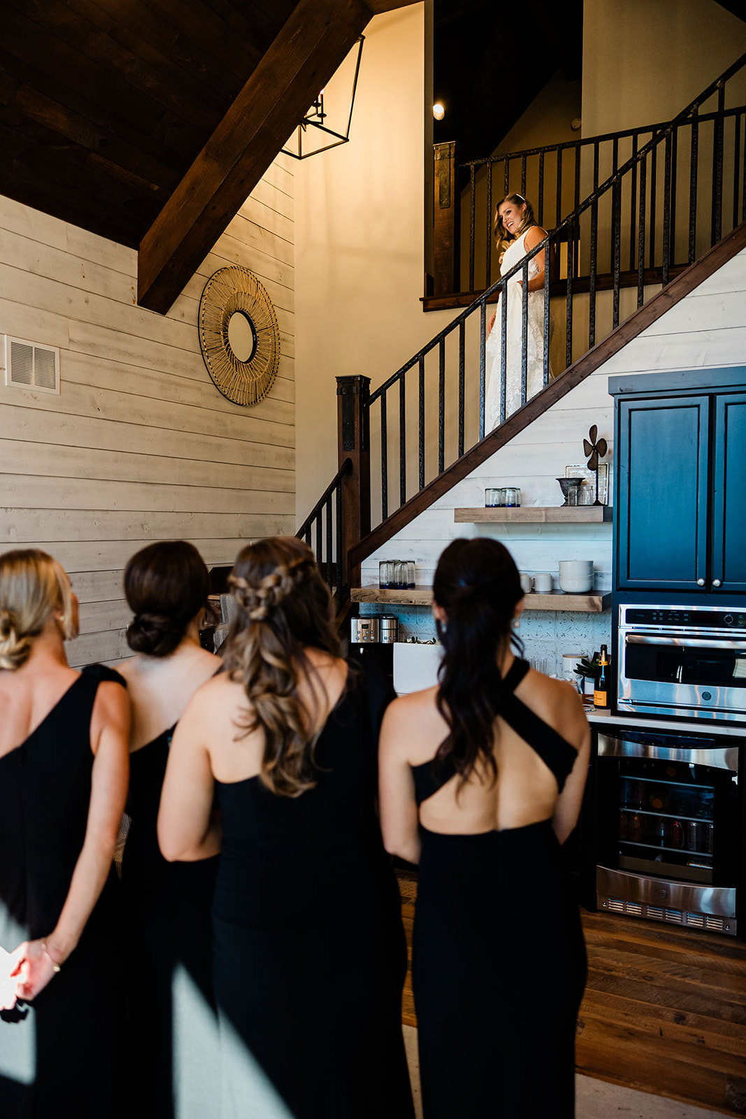 Bride descending the staircase to bridesmaids waiting below — staircase reveal at The Cove