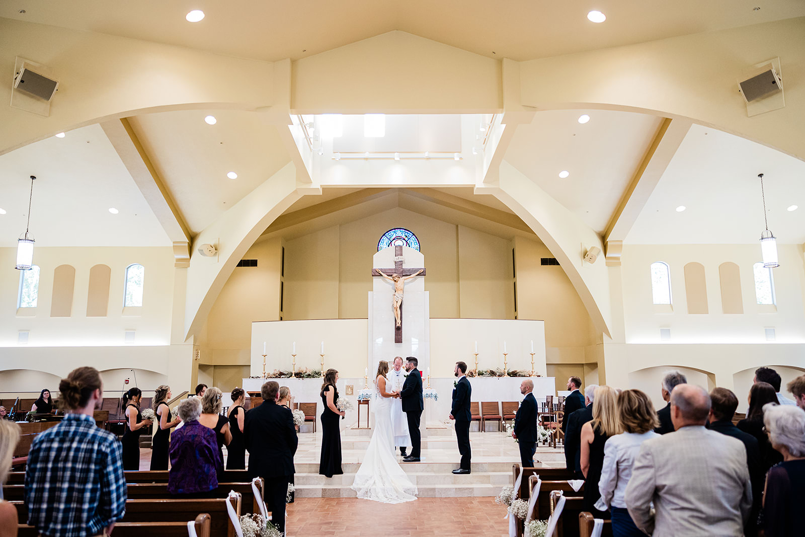 Wedding ceremony at the altar of Immaculate Heart Catholic Church in Crosslake, MN — arched ceiling and pendant lights