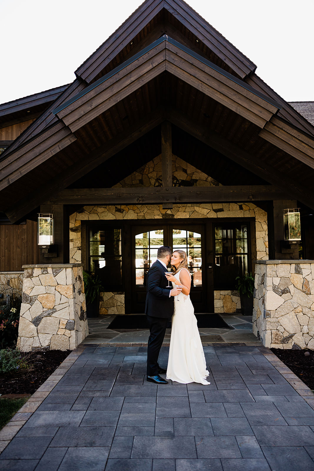 Couple kissing in front of the stone and timber entrance at The Cove on Whitefish Lake