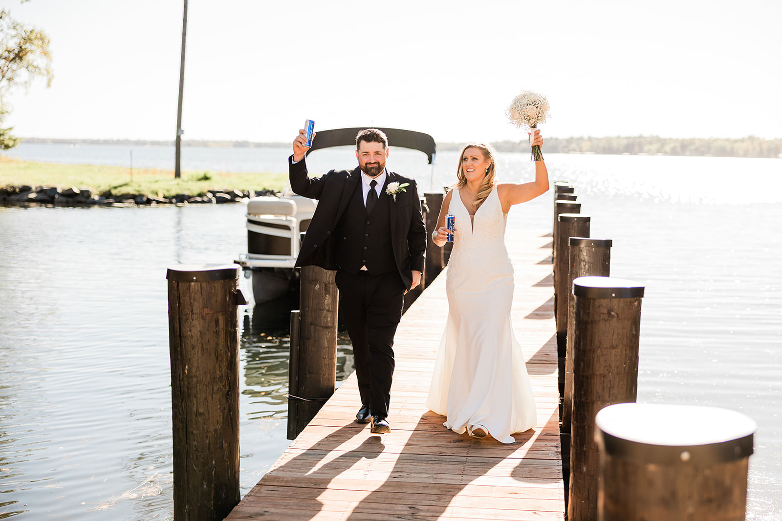 Couple walking down the dock at The Cove after arriving by boat — arms raised in celebration