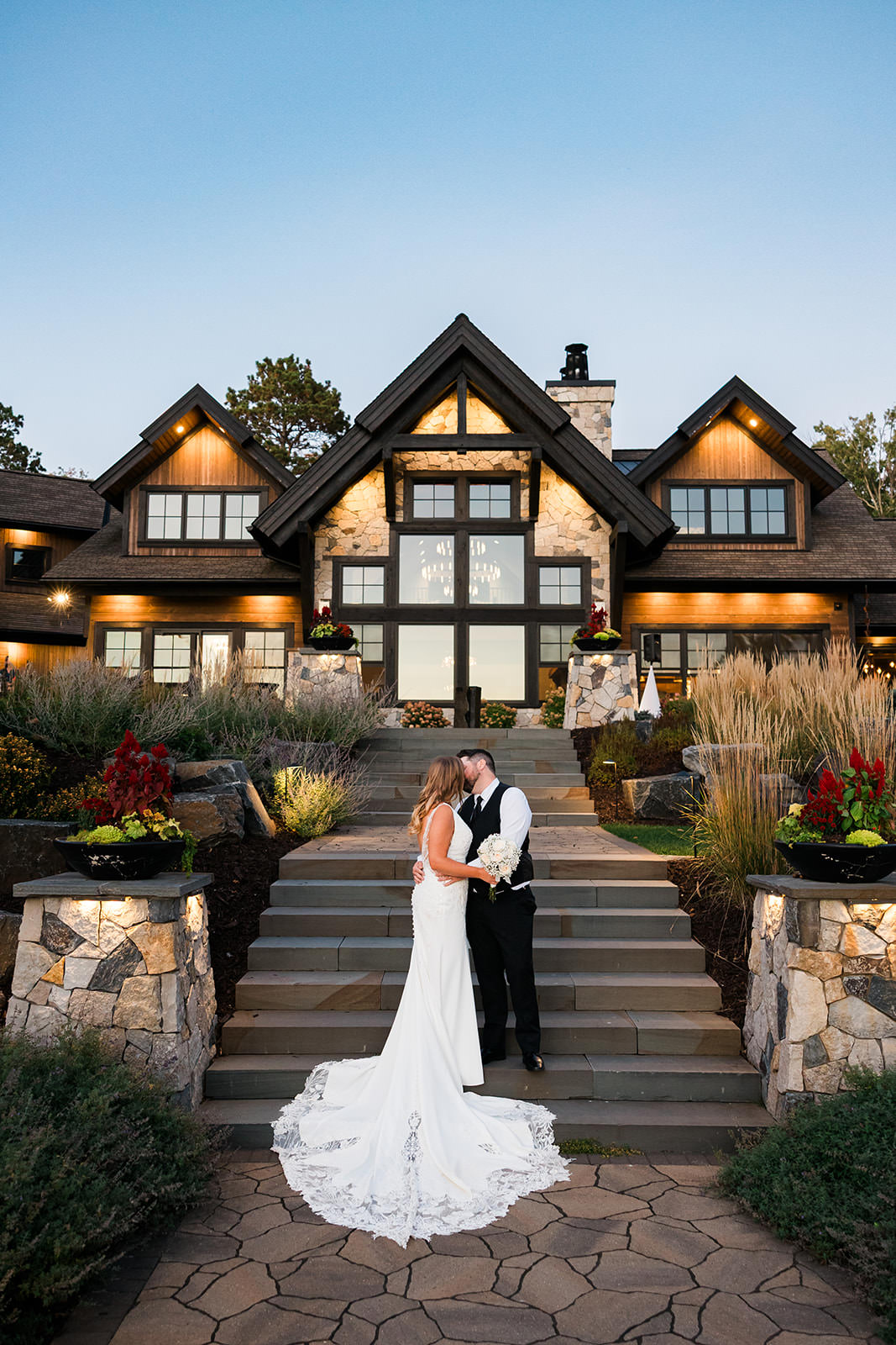 Couple in front of The Cove at dusk with landscape lighting — Crosslake, MN