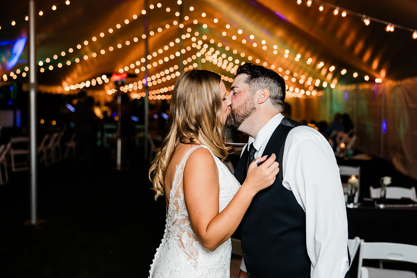 Couple kissing under string lights inside the reception tent — Whitefish Lake wedding