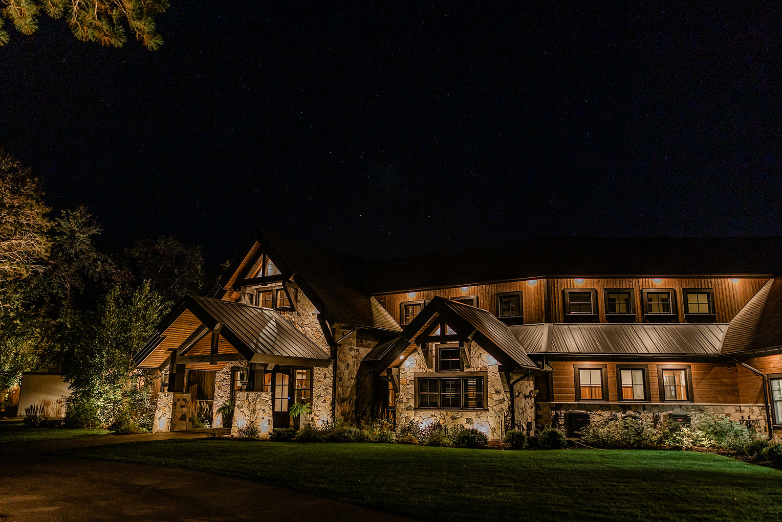 The Cove on Whitefish Lake lit up at night — stone and timber lodge under the stars