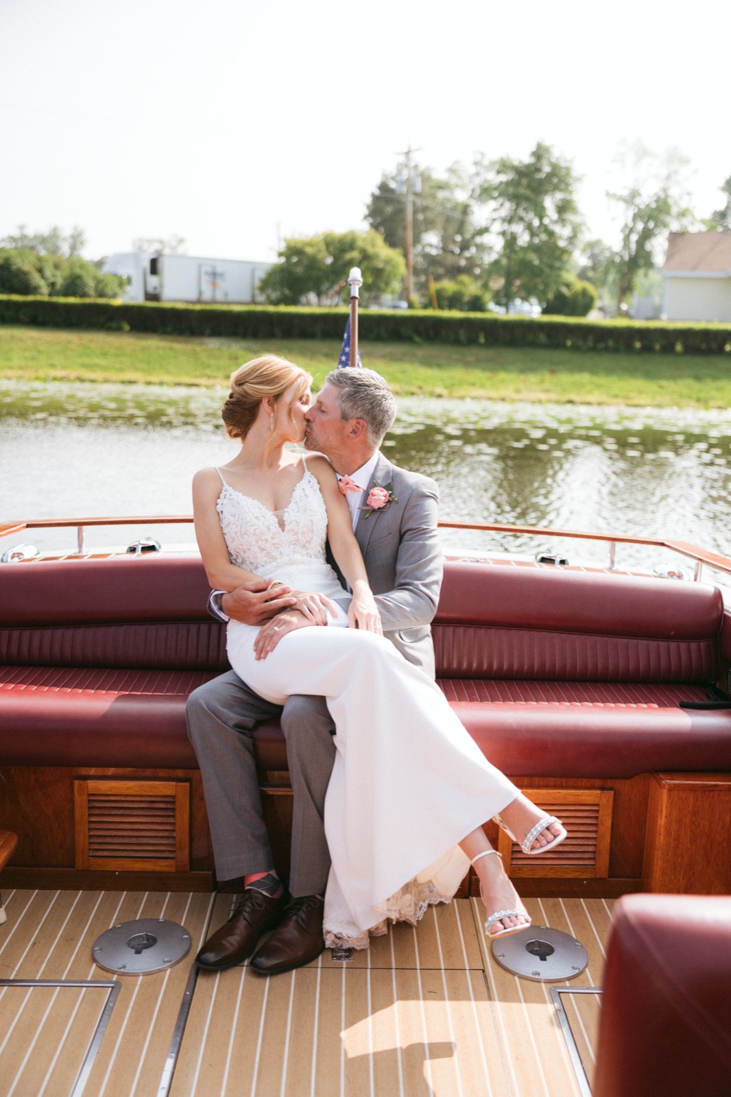 Melissa and Kody seated on the red leather bench of a classic wooden boat on Gull Lake, warm wood tones framing the couple at Madden's — Tim Larsen Photography, Brainerd Lakes MN