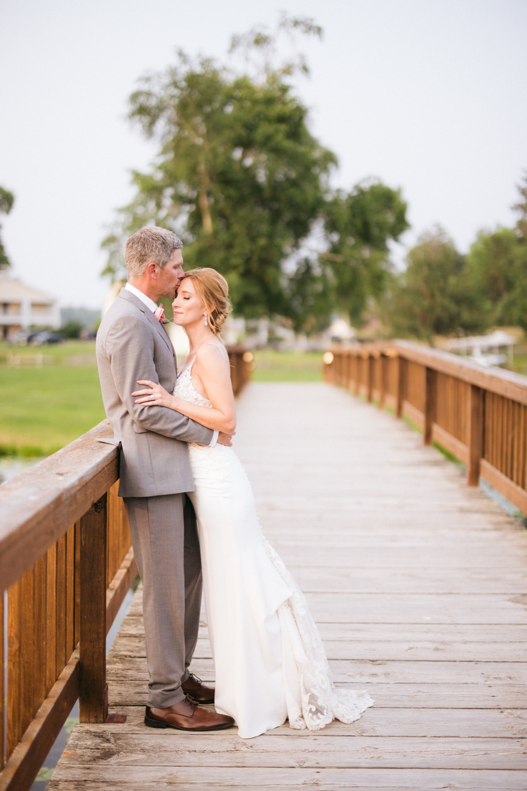 Melissa and Kody walk along a long wooden footbridge over the lake at Madden's, leading lines pulling the eye through receding railings — Tim Larsen Photography, Brainerd Lakes MN