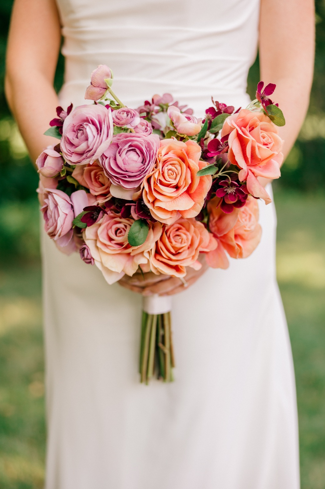 Monika holds her bouquet of coral, blush, and mauve roses with deep burgundy accents against her white wedding gown — Tim Larsen Photography, Brainerd Lakes MN
