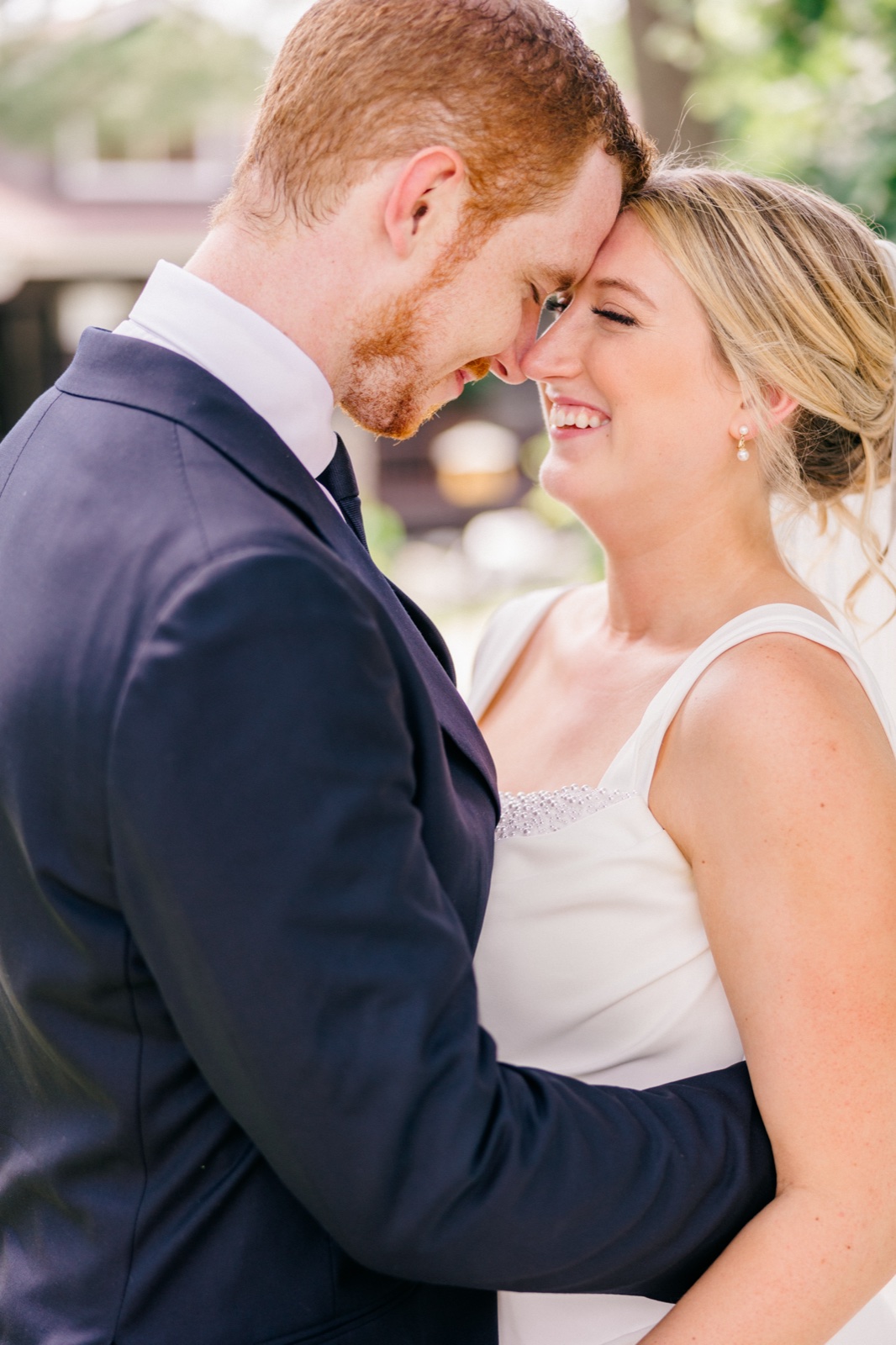 The bride laughs with closed eyes as she rests her forehead against the groom's in soft afternoon light outside the venue — Tim Larsen Photography, Brainerd Lakes MN