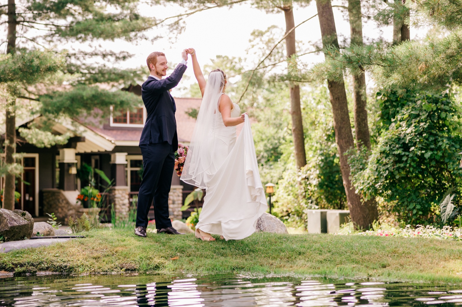 Mats twirls Monika beside a small pond on the lawn outside Grand View Lodge, her veil and dress trailing in motion — Tim Larsen Photography, Brainerd Lakes MN