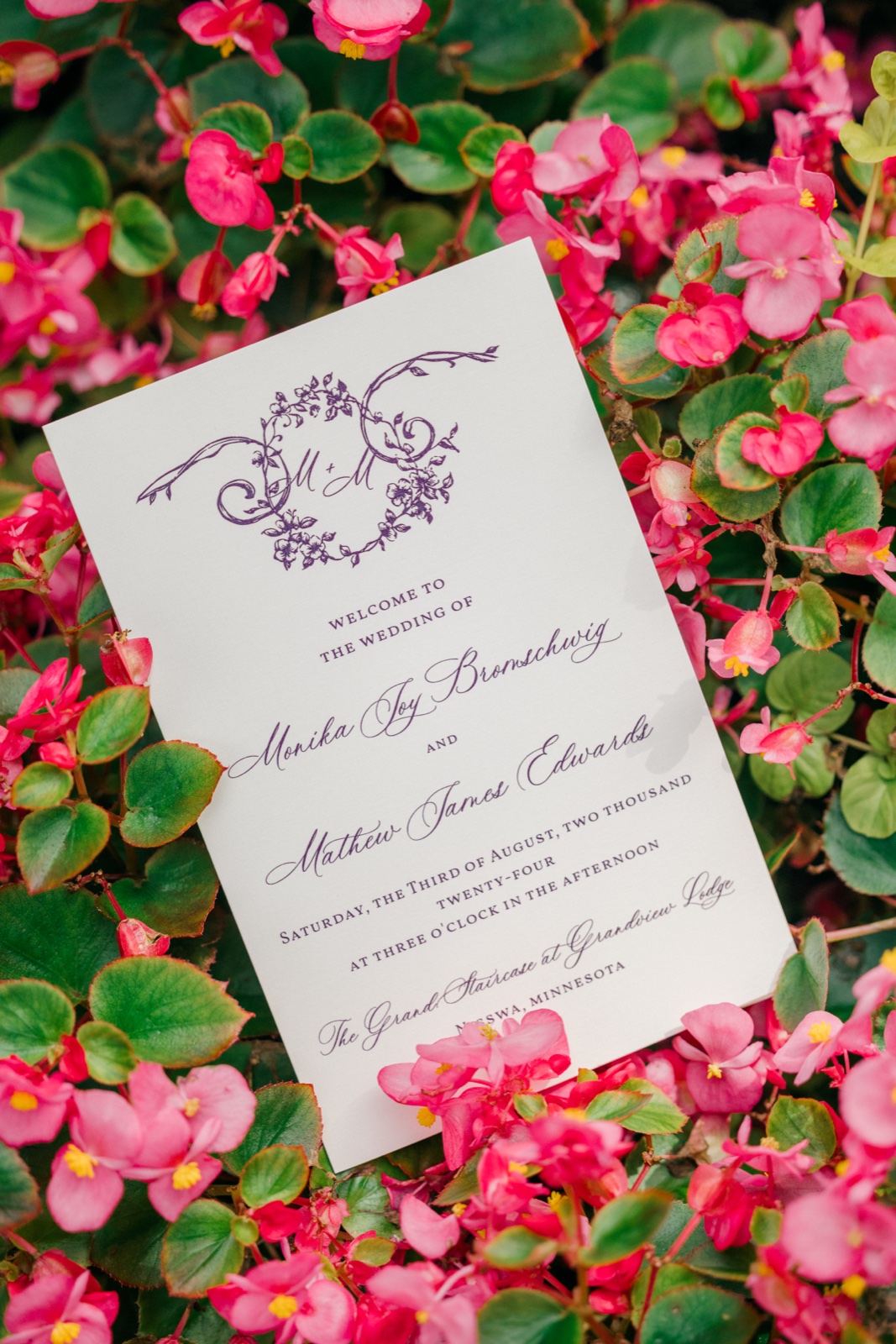 Wedding program for Monika and Mathew resting in a bed of bright pink begonias outside Grand View Lodge — Tim Larsen Photography, Brainerd Lakes MN