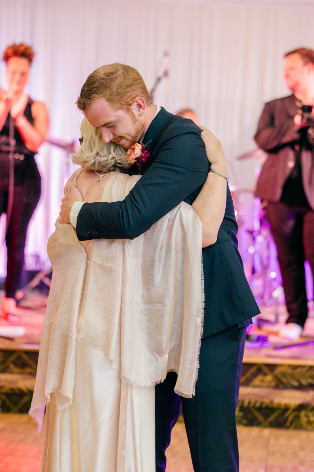 The groom holds his mother in a long embrace on the dance floor as the live band plays softly in the background — Tim Larsen Photography, Brainerd Lakes MN