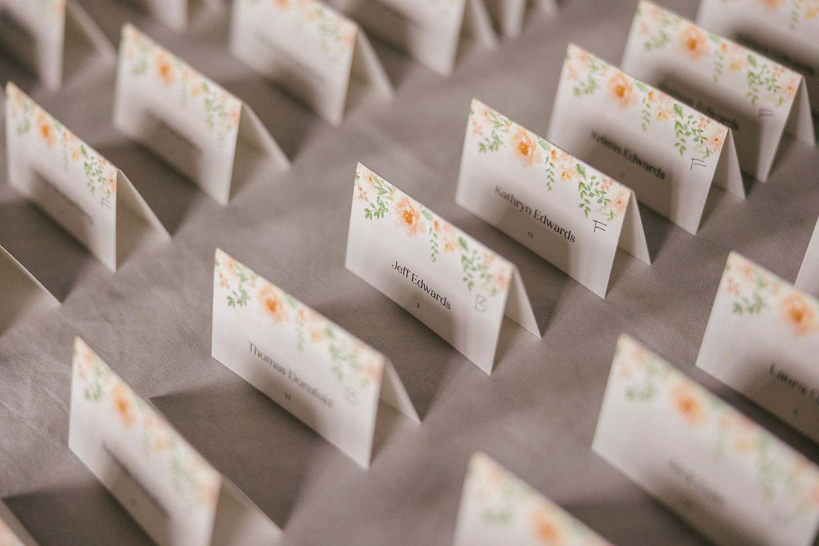 Watercolor floral escort cards arranged on a table — reception details — Tim Larsen Photography, Brainerd Lakes MN