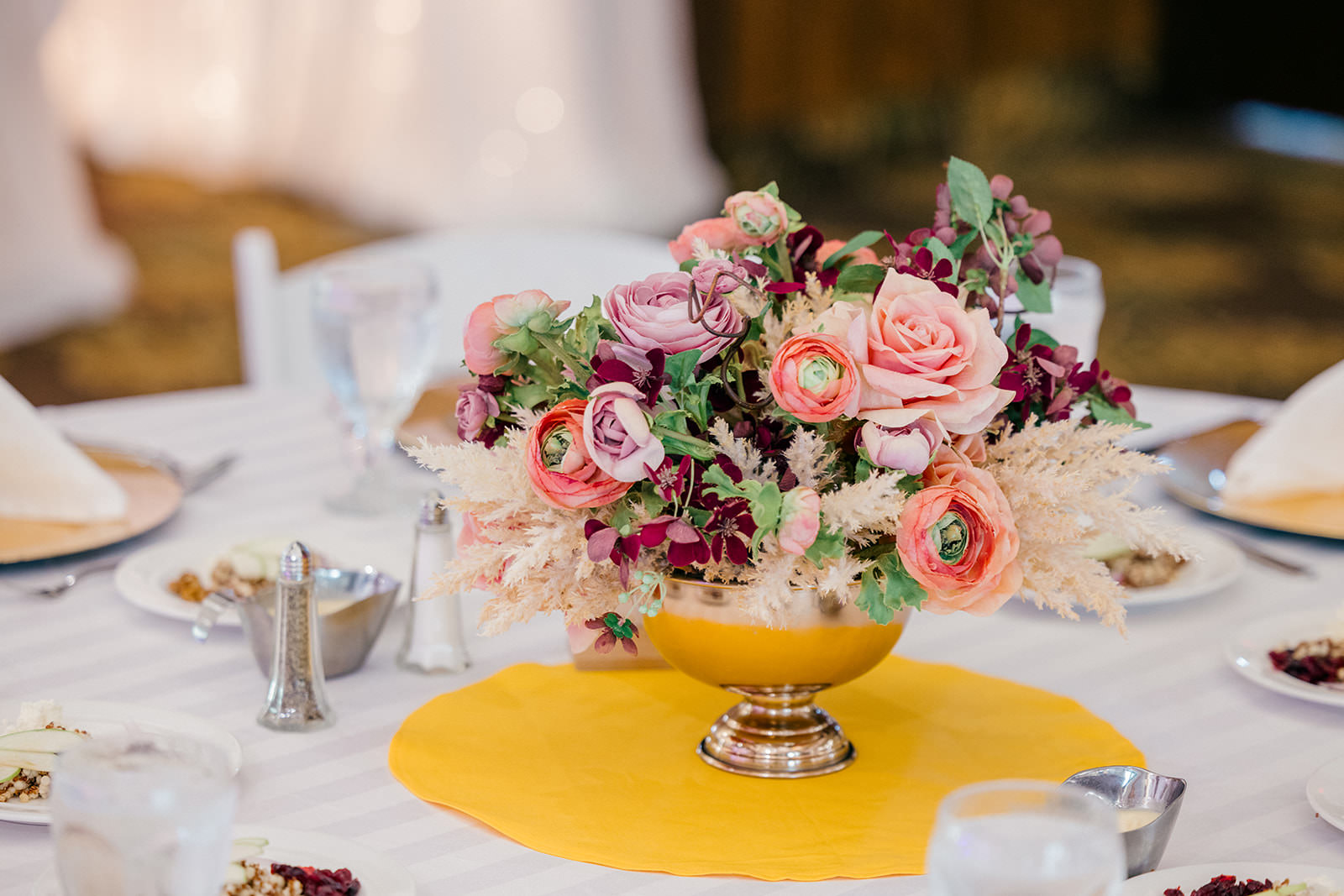 Reception centerpiece with roses in a gold vessel on a yellow placemat — Tim Larsen Photography, Brainerd Lakes MN