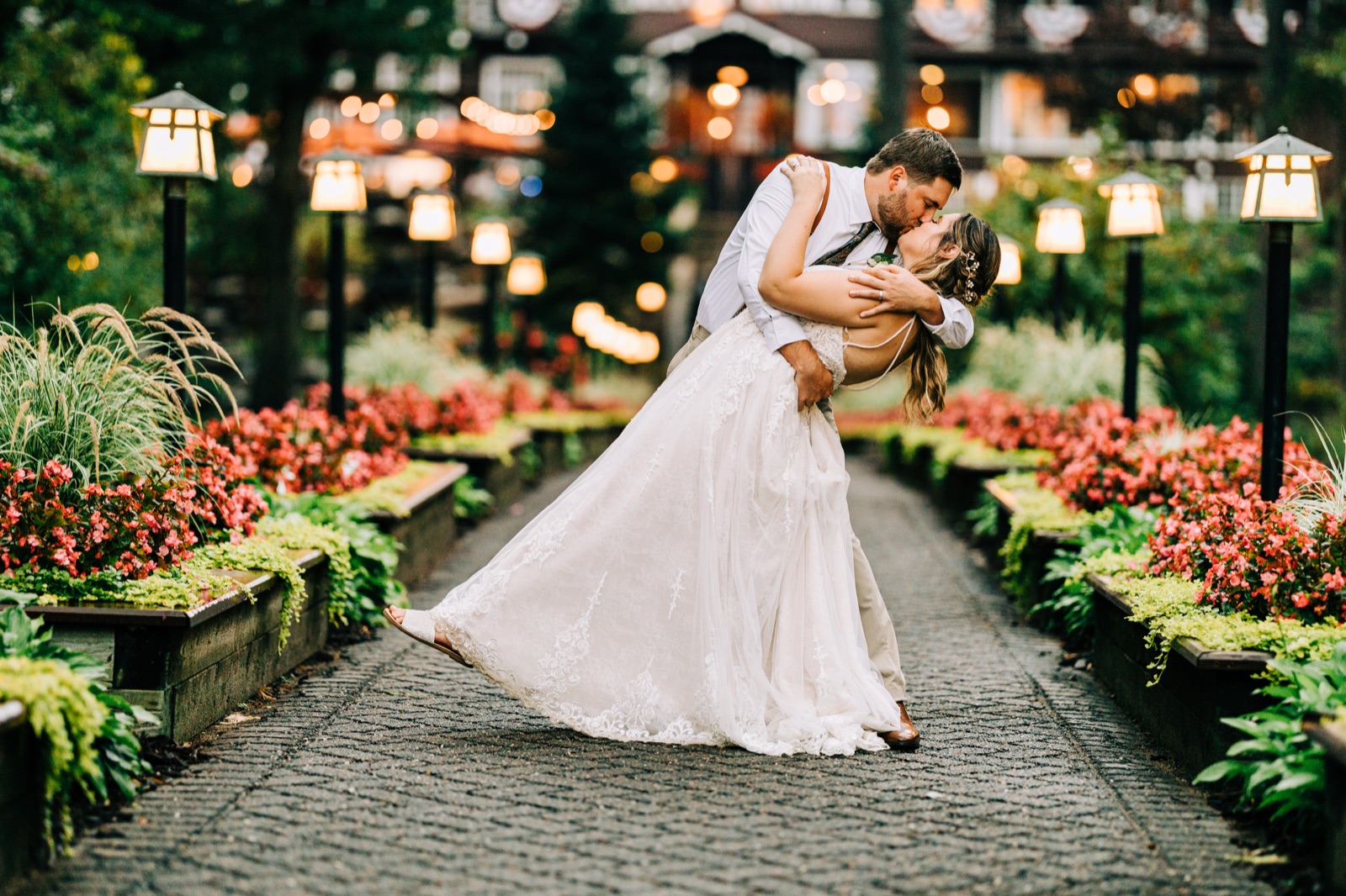 Lantern-lined garden path framing a dusk dip kiss with glowing lodge bokeh — Grand View Lodge — Tim Larsen Photography, Brainerd Lakes MN