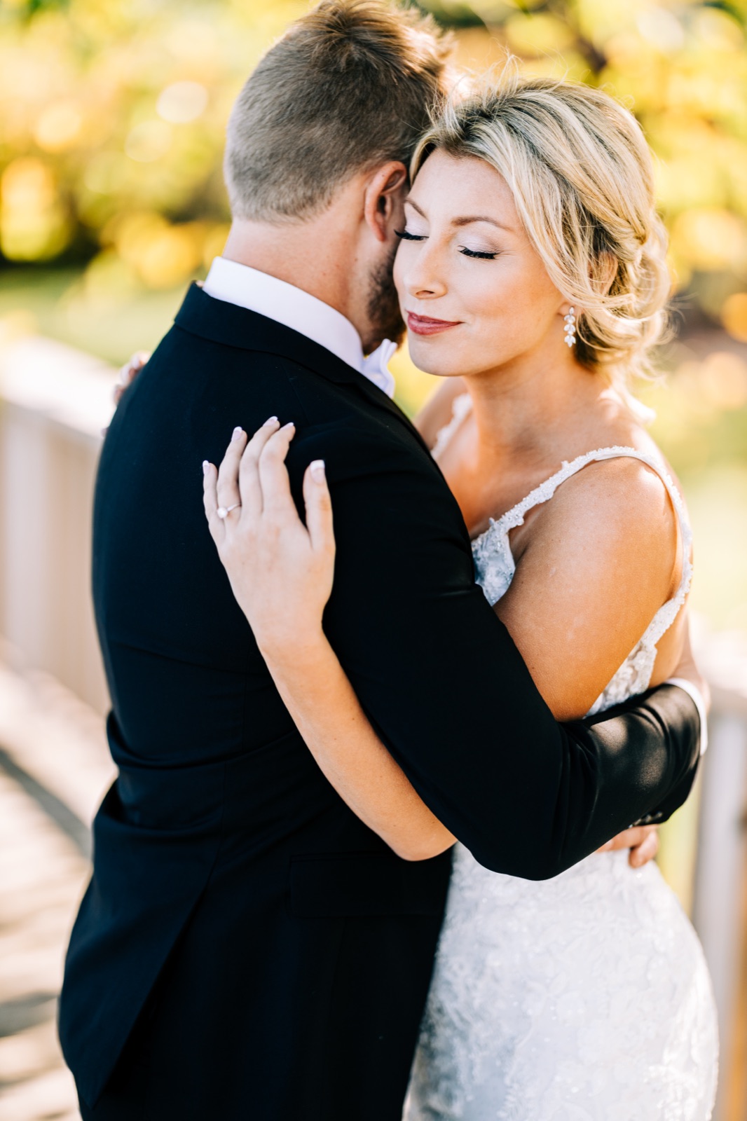Tight embrace with bride's serene face in golden backlight against glowing bokeh — Breezy Point Resort — Tim Larsen Photography, Brainerd Lakes MN