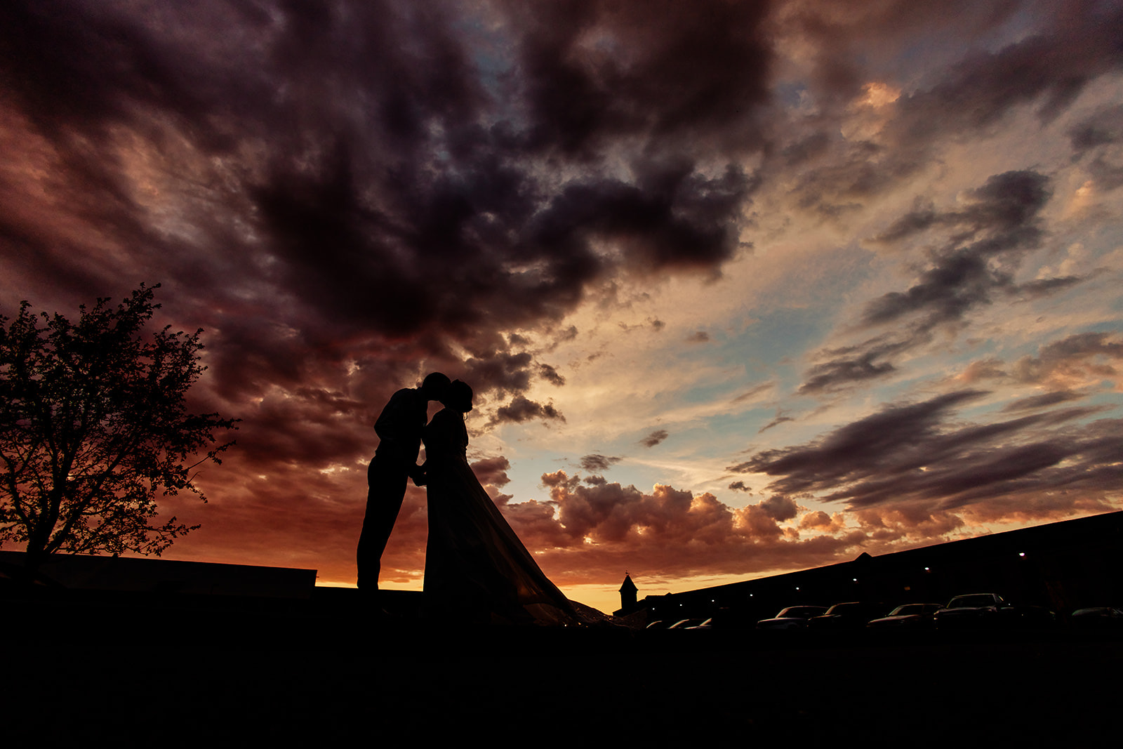 Silhouetted couple kissing under painterly sunset sky with veil trailing — rooftop portrait at the Northern Pacific Center — Tim Larsen Photography, Brainerd Lakes MN