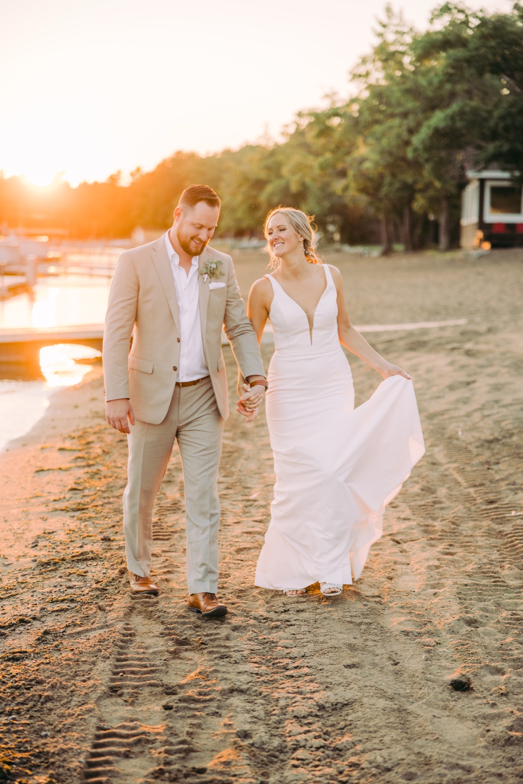Couple walking across sandy beach with sun flares low behind them — Grand View Lodge — Tim Larsen Photography, Brainerd Lakes MN