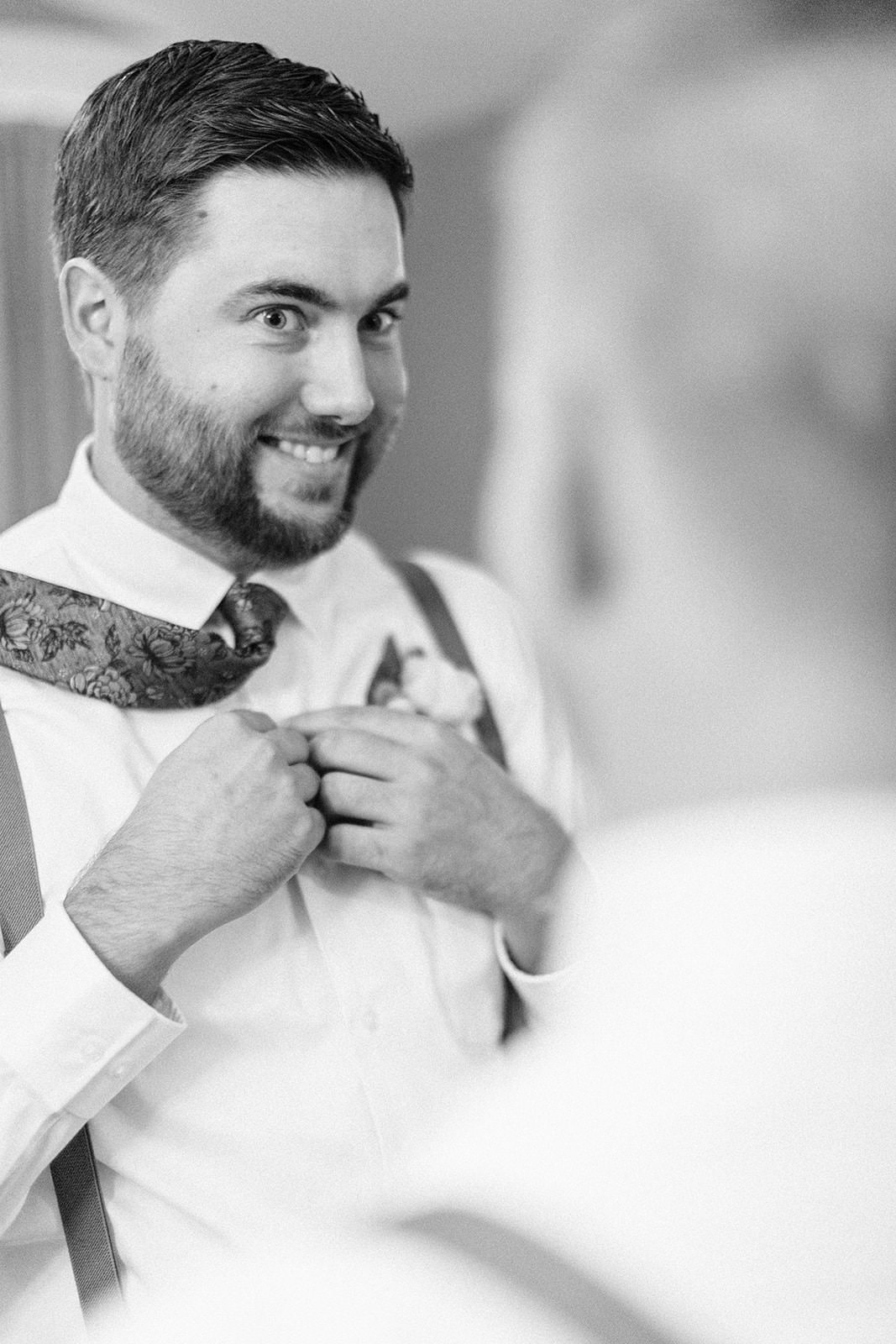 Jon adjusting his floral tie — black and white groom portrait — Tim Larsen Photography, Brainerd Lakes MN