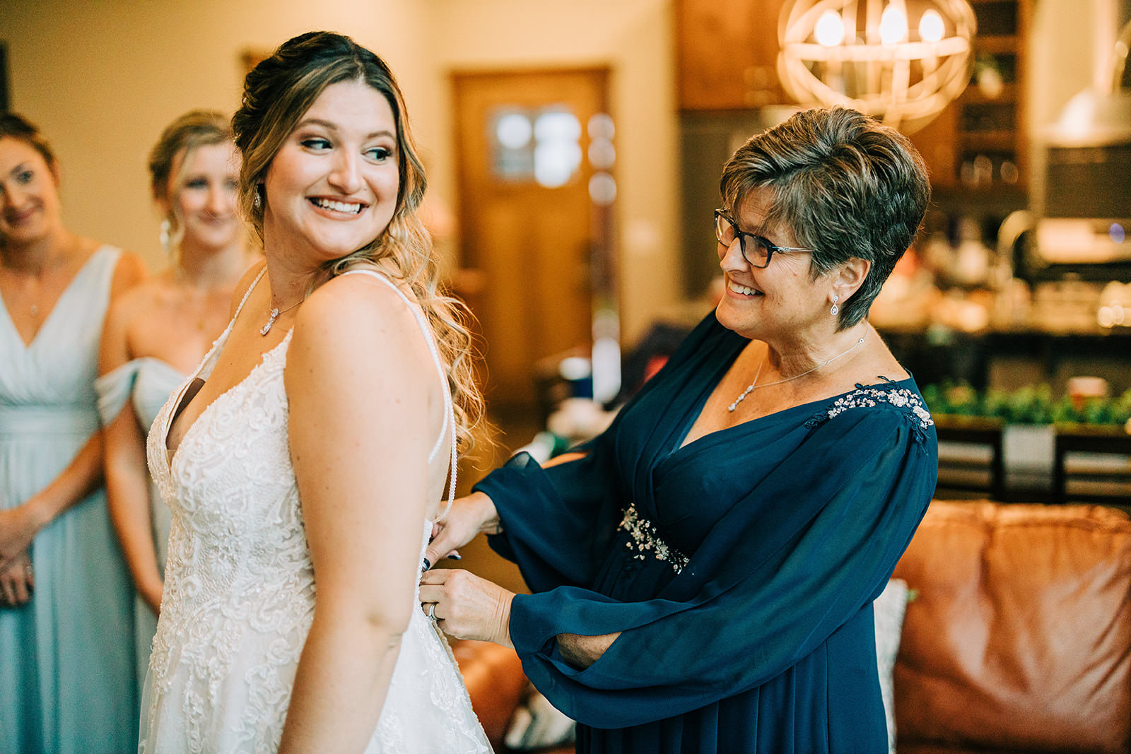 Shannon's mom buttoning the dress — bridesmaids watching in the background — Tim Larsen Photography, Brainerd Lakes MN