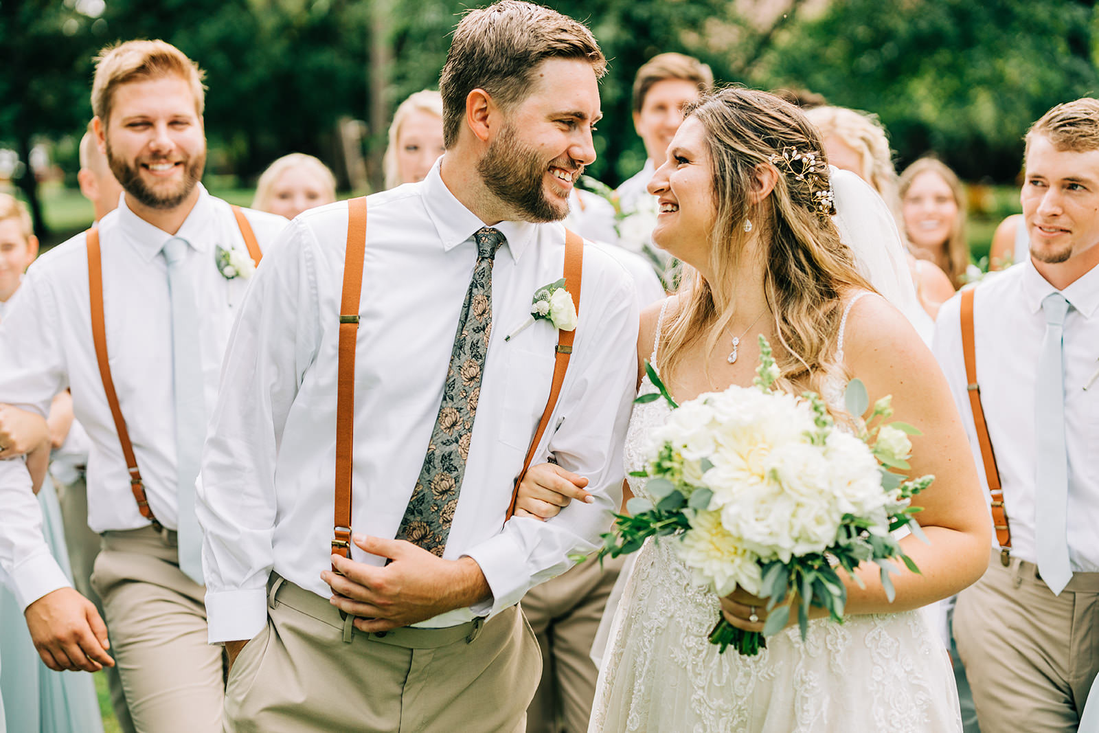 Shannon and Jon walking with the full wedding party — leather suspenders and sage dresses — Tim Larsen Photography, Brainerd Lakes MN