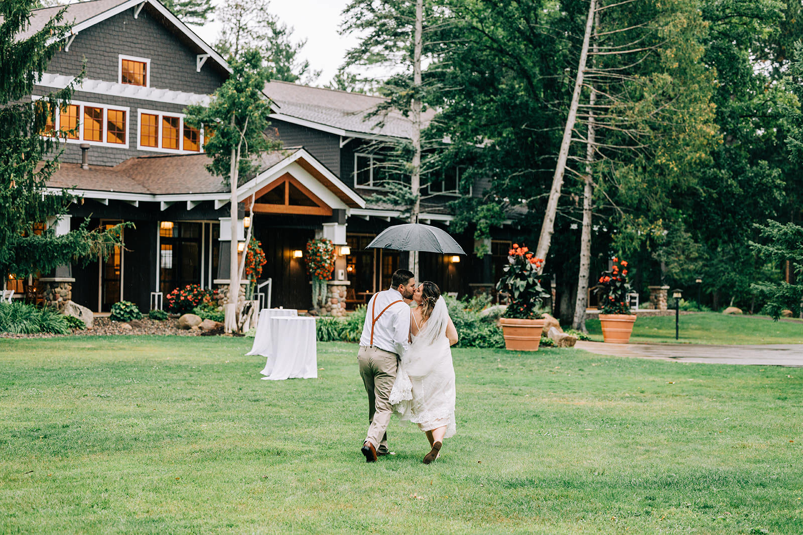 Shannon and Jon walking under an umbrella across the lawn — summer rain at Grand View Lodge — Tim Larsen Photography, Brainerd Lakes MN