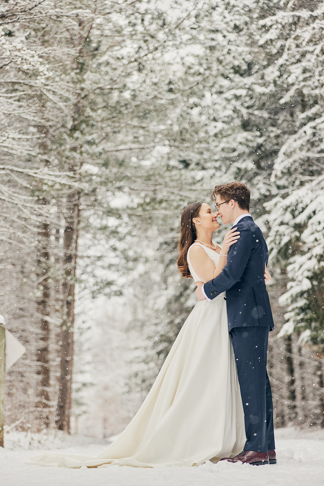 Couple kissing in the snow surrounded by snow-covered pines — winter wedding — Tim Larsen Photography, Brainerd Lakes MN