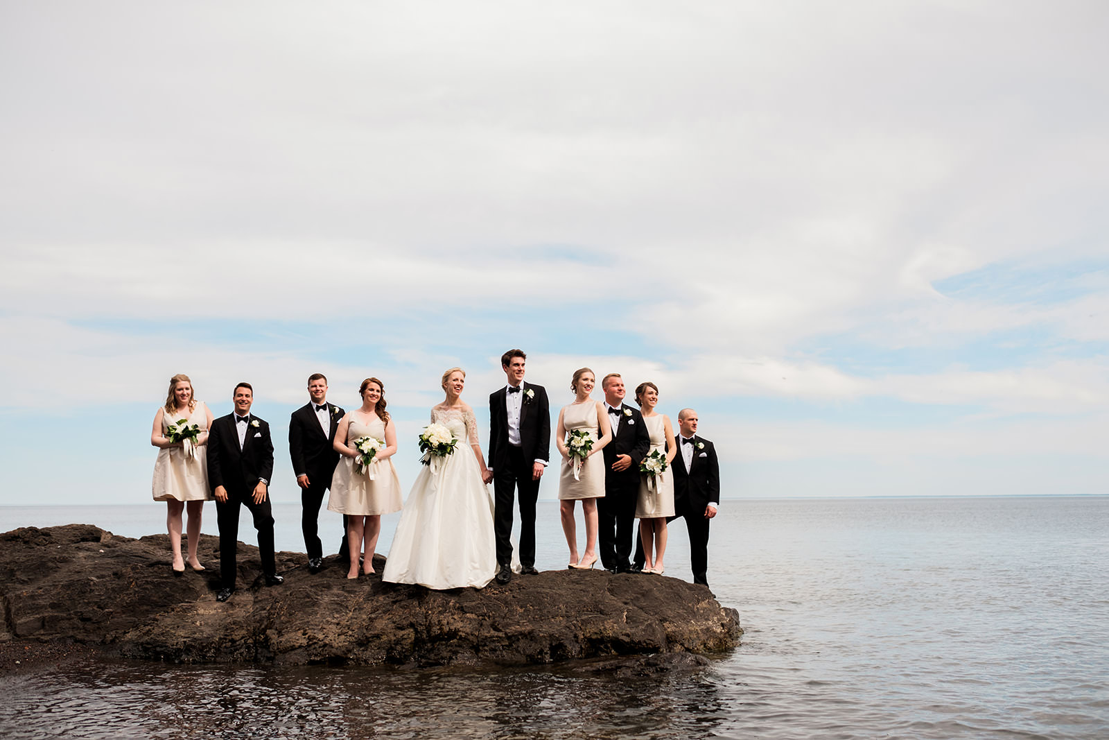 Full wedding party standing on the rocky Lake Superior shoreline — Tim Larsen Photography, Brainerd Lakes MN