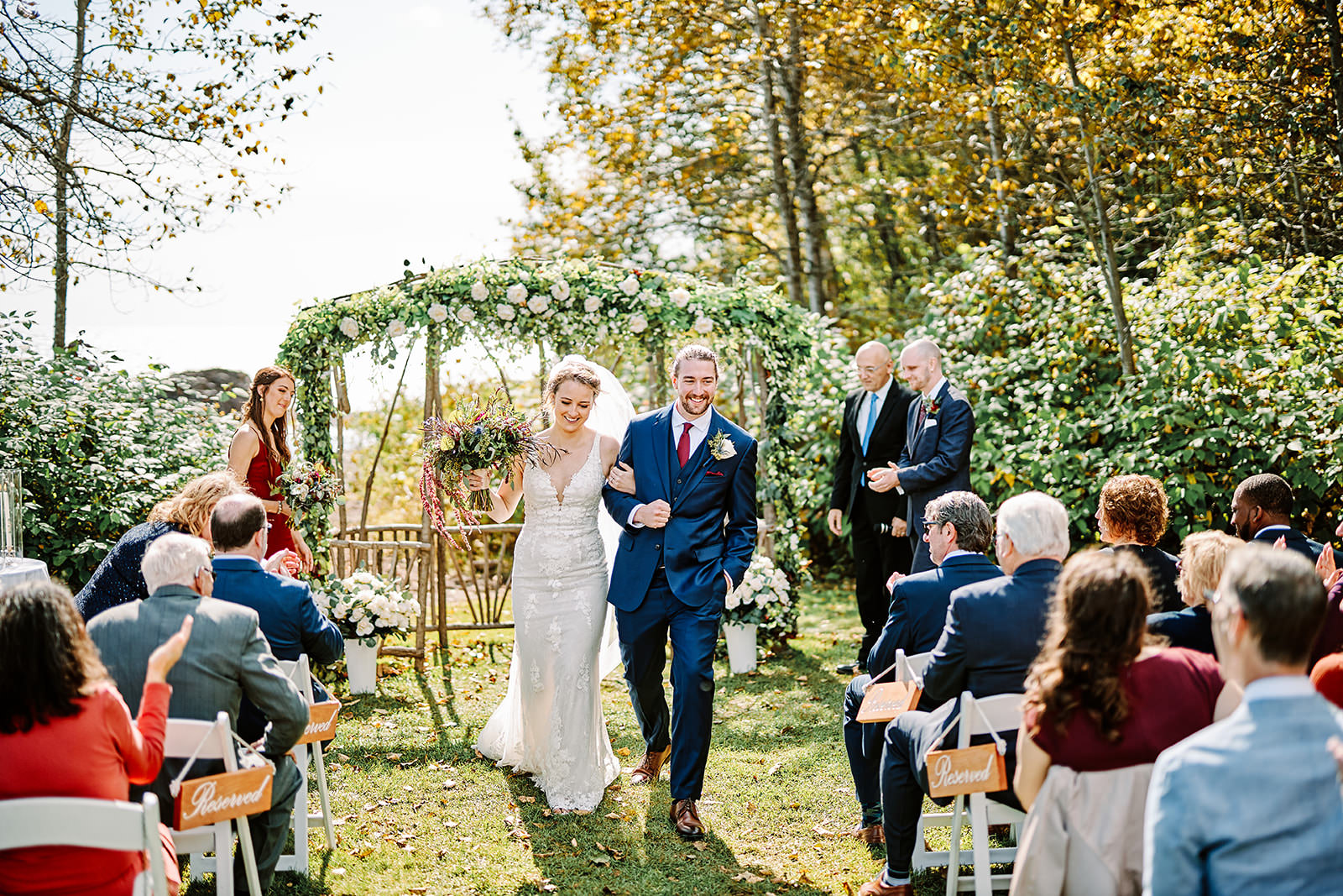 Outdoor ceremony under a greenery arch with guests — North Shore garden wedding — Tim Larsen Photography, Brainerd Lakes MN